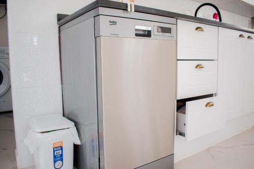 a white kitchen with a refrigerator and a trash can at villa Cristalina in Montevideo