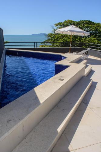 a swimming pool with an umbrella and a table with an umbrella at Mighil Hotel in Florianópolis