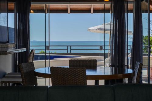 a dining room with a table and chairs and a view of the ocean at Mighil Hotel in Florianópolis