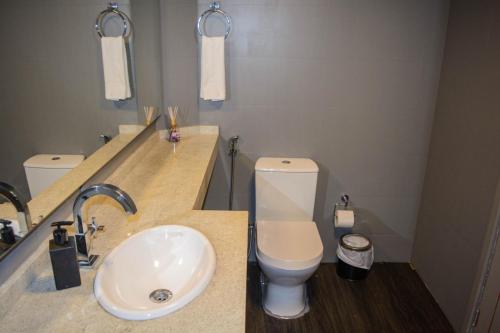 a bathroom with a white toilet and a sink at Mighil Hotel in Florianópolis