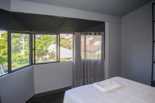 a bedroom with a bed and large windows at Mighil Hotel in Florianópolis