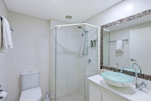 a bathroom with a shower and a sink and a toilet at Sandy Cove Apartment The Entrance 8 in The Entrance