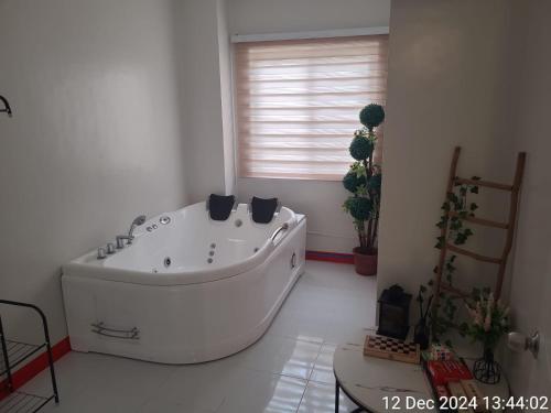 a large white bath tub in a room with a window at Serenity Homes with Indoor Jacuzzi in Lipa