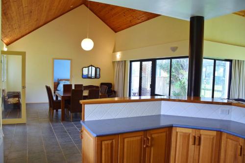 a kitchen with a blue counter top and a dining room at Lazy Choose-Day - Bring your own linen. in Hat Head