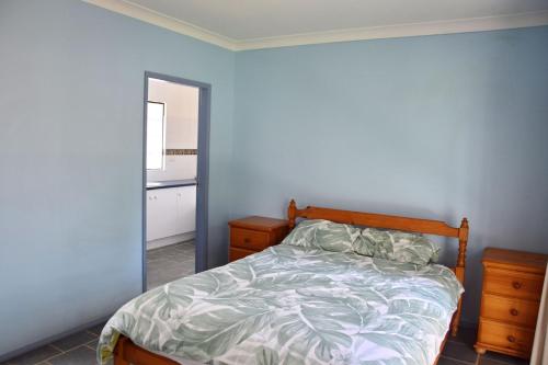 a bedroom with a bed and a blue wall at Lazy Choose-Day - Bring your own linen. in Hat Head