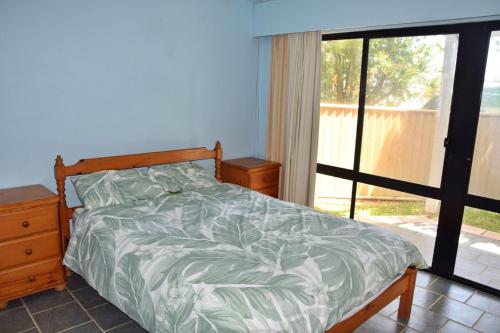 a bedroom with a bed and a sliding glass door at Lazy Choose-Day - Bring your own linen. in Hat Head