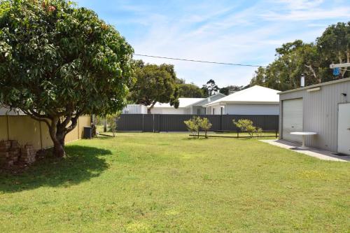 a yard with a tree and a fence at Lazy Choose-Day - Bring your own linen. in Hat Head