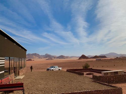 a person standing next to a building in the desert at Wadi Rum Travel camp in Wadi Rum