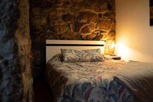 a bed in a room with a stone wall at Casa da Cris in Cotelo