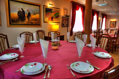 a table with a red table cloth and plates and silverware at Boutique Hotel Sulić in Međugorje
