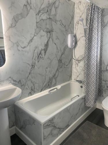 a white bathroom with a tub and a sink at Almondbank Cottage - 2 Bedrooms, 8 miles from Portree in Skeabost