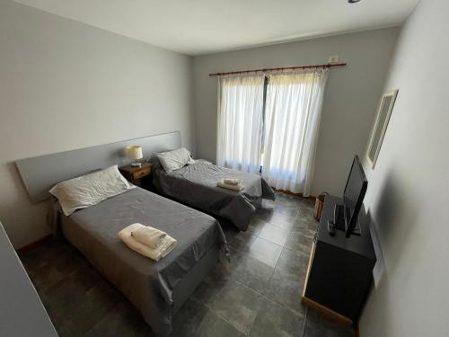 a bedroom with two beds and a television in it at Duplex LM in Chivilcoy