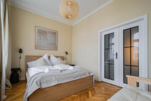 a bedroom with a bed with white sheets and a window at Radost Residence The Heart of Unique Living in Prague