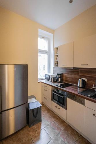 a kitchen with white cabinets and a stainless steel refrigerator at Radost Residence The Heart of Unique Living in Prague