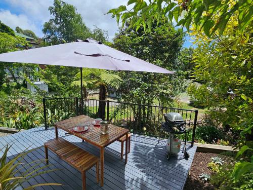 a patio with a table and an umbrella and a grill at Beautiful Apartment Surrounded by Native Bush in Picton
