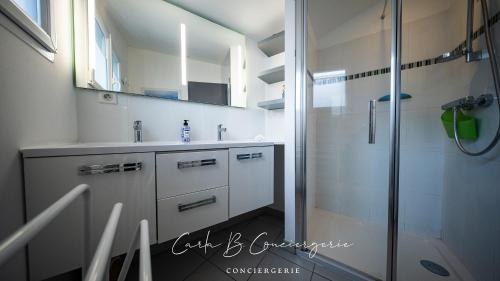 une salle de bain blanche avec une douche et un lavabo dans l'établissement MAISON LE BONHEUR Concarneau 4 personnes, à Concarneau