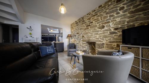 un salon avec un canapé et un mur en pierre dans l'établissement MAISON LE BONHEUR Concarneau 4 personnes, à Concarneau