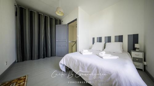 une chambre avec un lit blanc avec deux serviettes dessus dans l'établissement MAISON LE BONHEUR Concarneau 4 personnes, à Concarneau
