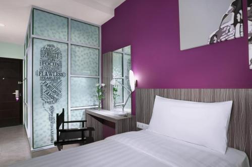a bedroom with a white bed and a purple wall at OS Style Hotel Batam Powered by Archipelago in Batu Aji