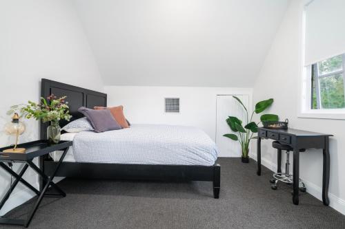 a white bedroom with a bed and two tables at Tree Tops on Hodge in Albury