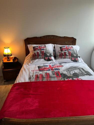 a bed with a red blanket and pillows on it at Appartement calme, frais à louer, nouvellement repeint, emplacement stratégique, proche de toutes commodités, de l'autoroute, valenciennes, lille, Belgique, wifi, Netflix, parking Gratuits in Raismes