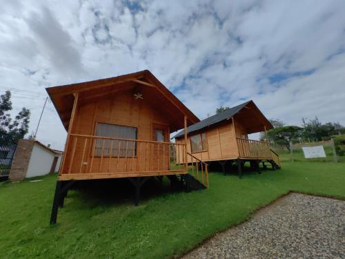 two wooden huts on a grass field with a sky at Cabañas El Condominio in Guatavita
