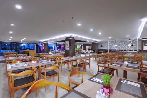 un restaurante con mesas y sillas de madera en OS Style Hotel Batu Aji Batam Powered by Archipelago, en Batu Aji