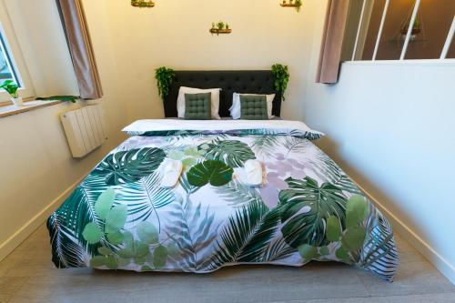 - un lit avec un couvre-lit bleu et vert orné de plantes dans l'établissement A 100 M DE LA VIELLE VILLE, PROCHE REMPARTS, cosy holiday, à Boulogne-sur-Mer