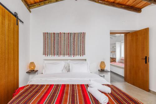 a bedroom with a bed with a red and white rug at Casa do Jardim Secreto - Monsaraz in Santo António do Baldio