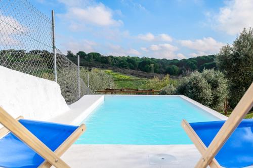 a blue swimming pool with two chairs and a fence at Casa do Jardim Secreto - Monsaraz in Santo António do Baldio