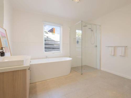 a white bathroom with a tub and a glass shower at Lyons in Port Fairy