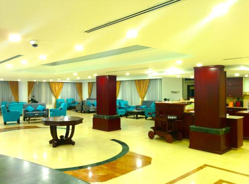 a large lobby with blue chairs and a table at City Inn Palace Hotel in Ramallah