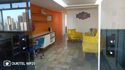 two views of a kitchen with yellow chairs in a room at Cobertura Duplex Vista do Mar in Recife