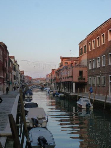 a canal with boats in a city with buildings at Appartamento Colonna in Murano