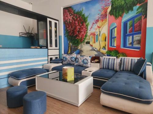 a living room with blue couches and a mural at White's house in Quan Lạn