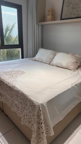 a bed with a white comforter and a window at VG Sun Cumbuco in Cumbuco