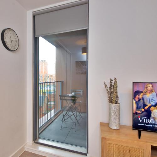 a large glass window in a living room with a clock at Modern 1-Bed Apartment Near City Centre, Arndale, Spinningfields, MediaCityUK, Old Trafford & Etihad, Sleeps 4, Netflix, Gym, Balcony, Nespresso Machine, Perfect for Long & Short Stays, Leisure, Contractors & Professionals! in Manchester
