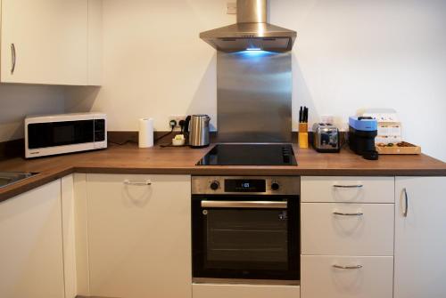 a kitchen with a stove and a microwave at Modern 1-Bed Apartment Near City Centre, Arndale, Spinningfields, MediaCityUK, Old Trafford & Etihad, Sleeps 4, Netflix, Gym, Balcony, Nespresso Machine, Perfect for Long & Short Stays, Leisure, Contractors & Professionals! in Manchester