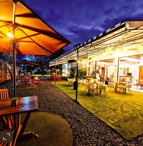 a patio with tables and chairs and umbrellas at night at Casa Hotel Bremen in Circasia
