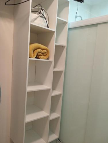 a walk in closet with white shelves at LOFT NOVO CONFORTÁVEL in Sorocaba