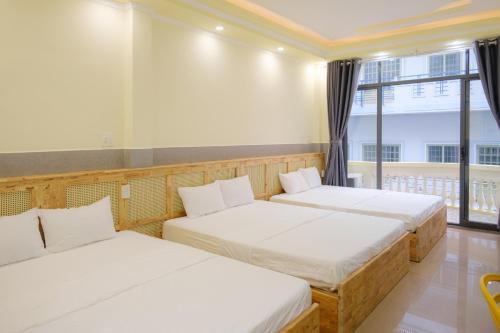 two beds in a room with a window at De Rivé Homestay Cần Thơ in Can Tho
