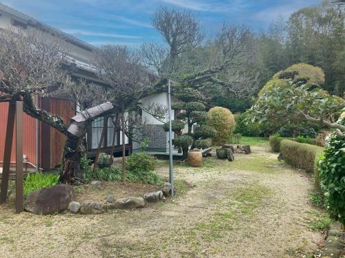 a garden with a tree and a house at ようこそ月の宿へ in Shindembaru
