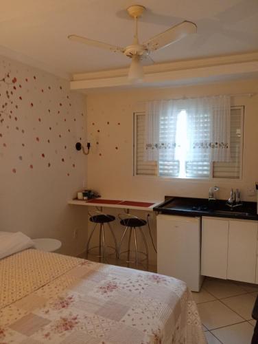 a bedroom with a bed and a kitchen with a ceiling fan at LOFT NOVO CONFORTÁVEL in Sorocaba