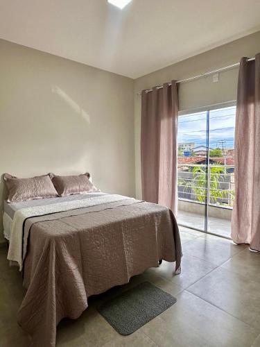 a bedroom with a bed and a large window at Apartamento Palmeira Espaço Conforto e Conectividade em Formosa in Formosa