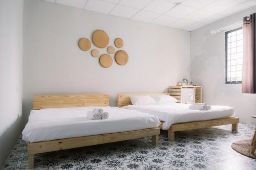 two twin beds in a room with white walls at De Rivé Homestay Cần Thơ in Can Tho