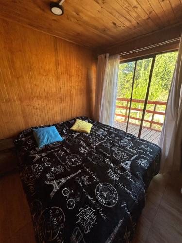 a bedroom with a bed with a black comforter at Casa Eco Bosque in Pichilemu
