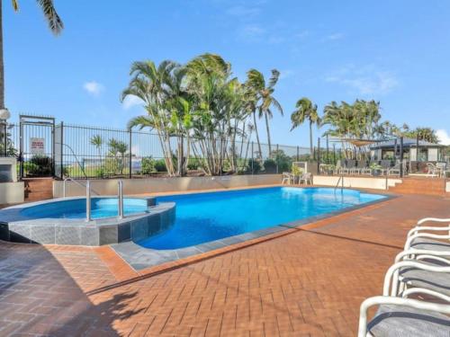 ゴールドコーストにあるOcean Front Escape on Palm Beachの椅子とヤシの木のあるプール