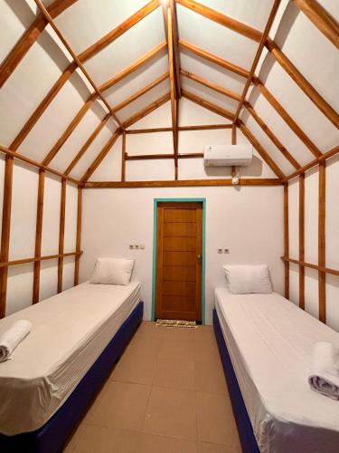 two beds in a room with a door at MAI LAKU Cottage in Sekotong