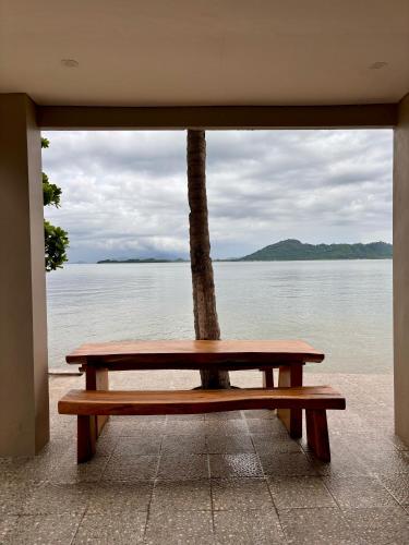 a wooden bench sitting in front of the water at MAI LAKU Cottage in Sekotong