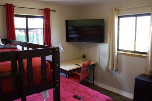 a bedroom with a bed and a desk and a television at Private Home - Playground, Jumping Mat, BBQ, Darts, Firepit, Gazebo, 4 Smart TVs, White Cotton Bedding, - The Redwood Cul-De Sac Beach Retreat in Crescent City